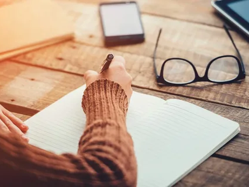 Person writing in a notebook on a desk